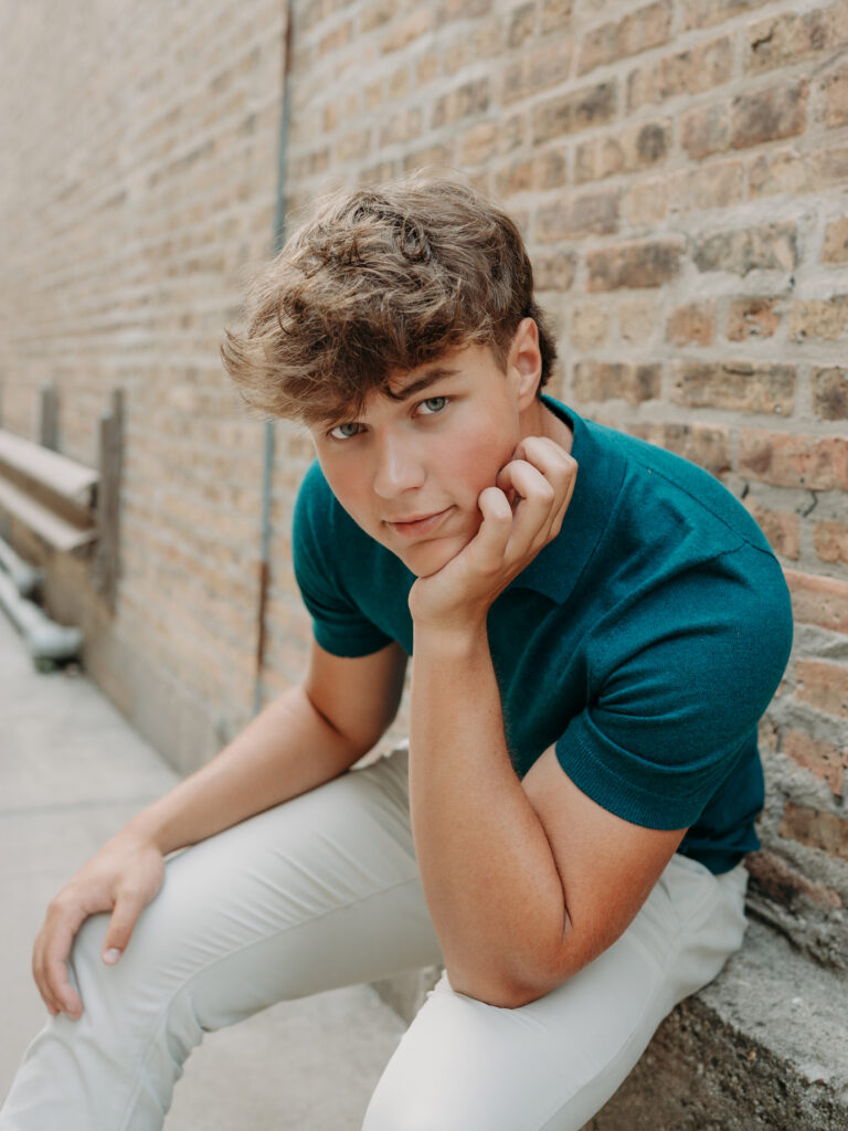 High school senior boy in an editorial pose in a downtown brick alley — urban senior portraits near Chicago northwest suburbs