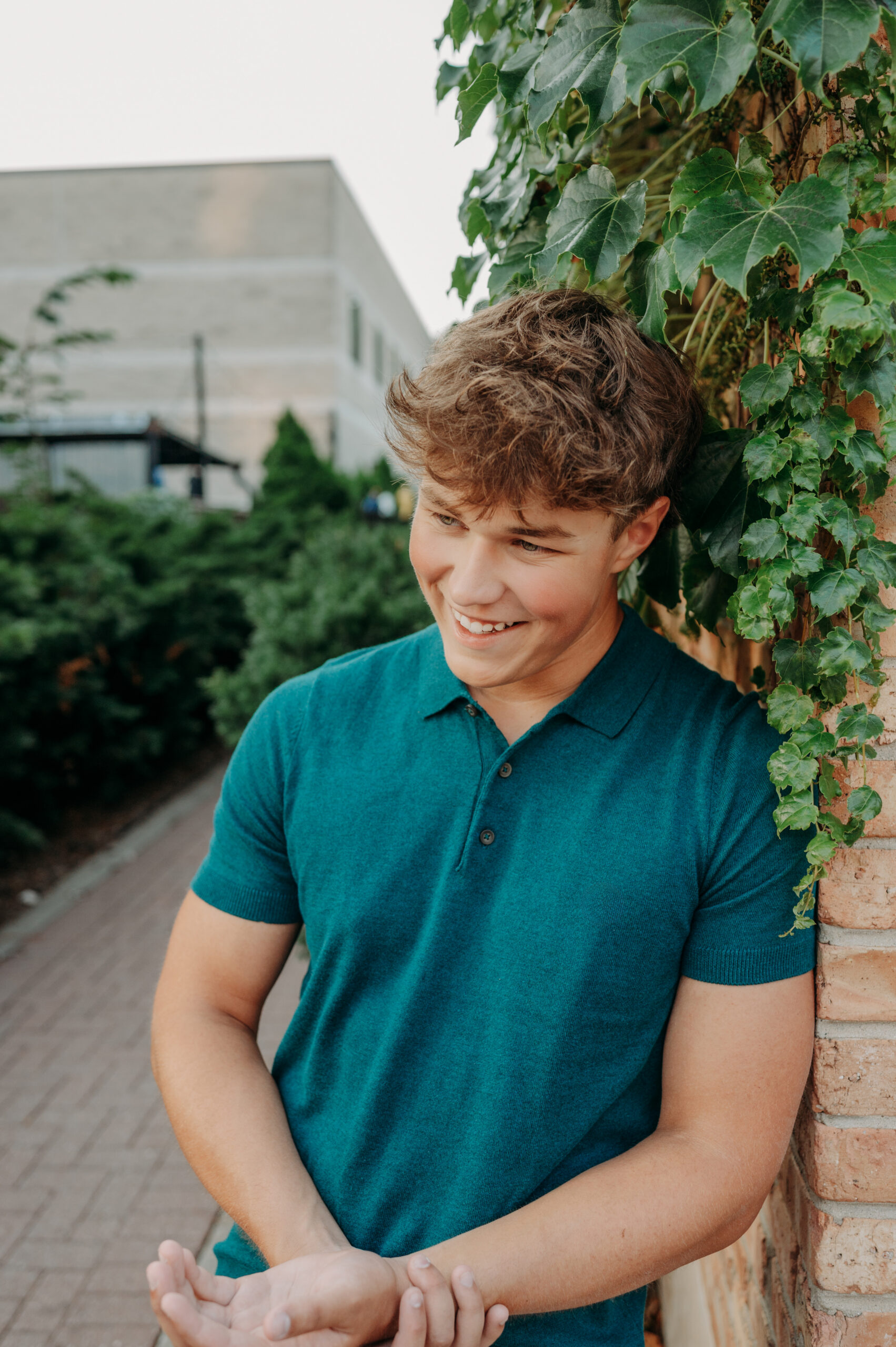 Senior boy laughing against a brick wall covered in ivy in an urban downtown setting — senior pictures in Barrington and Arlington Heights IL