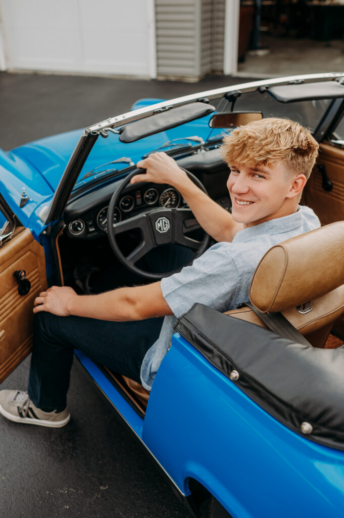 Senior boy sitting in a classic blue MG convertible for his senior portraits — meaningful personalized senior session near Chicago