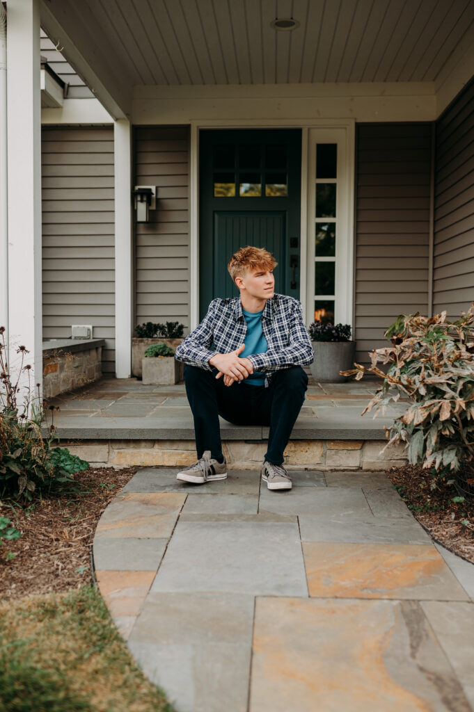 High school senior boy sitting on the stone front steps of his home — personalized senior portraits at home in Barrington IL