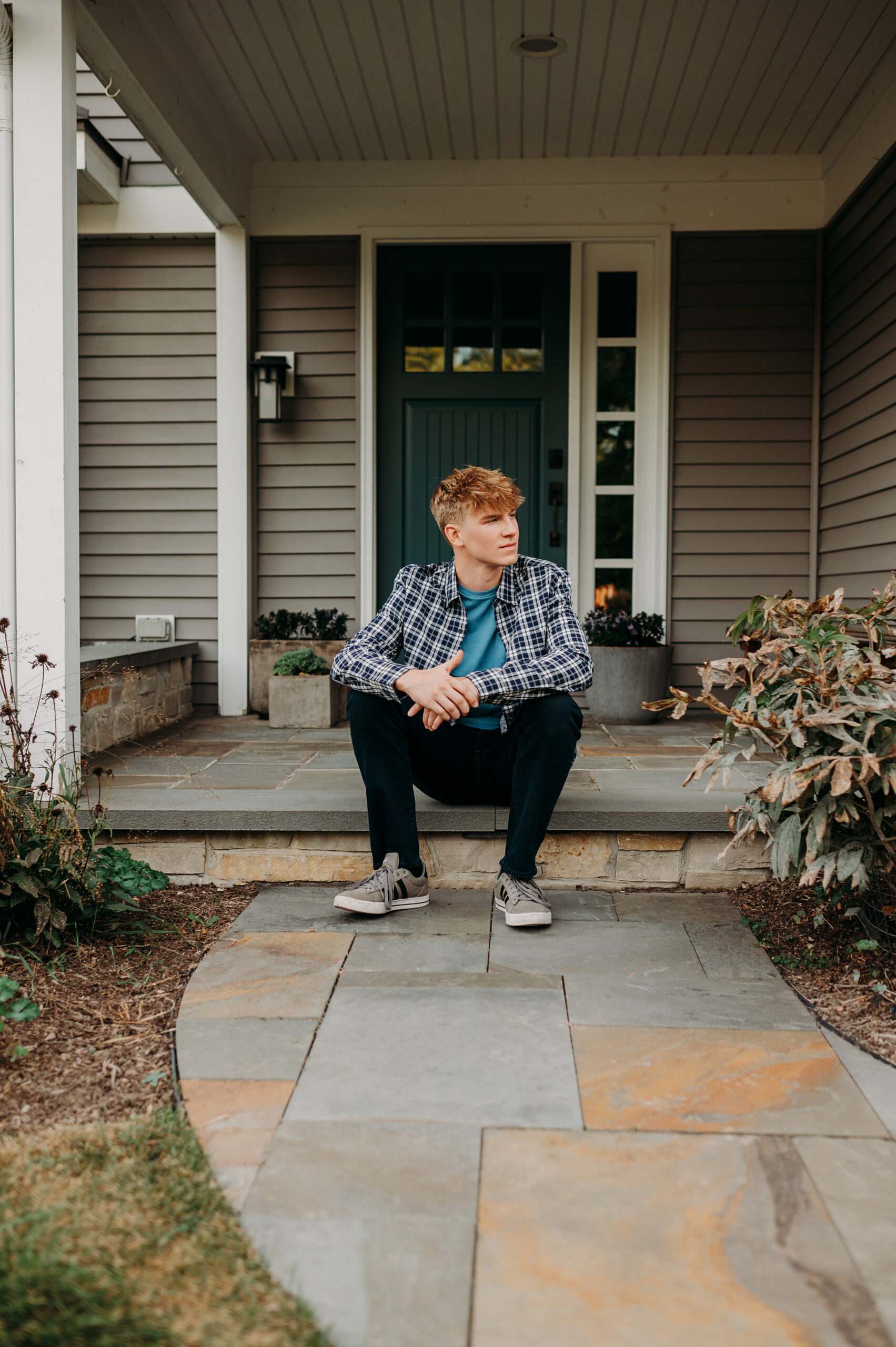 High school senior boy sitting on the stone front steps of his home — personalized senior portraits at home in Barrington IL