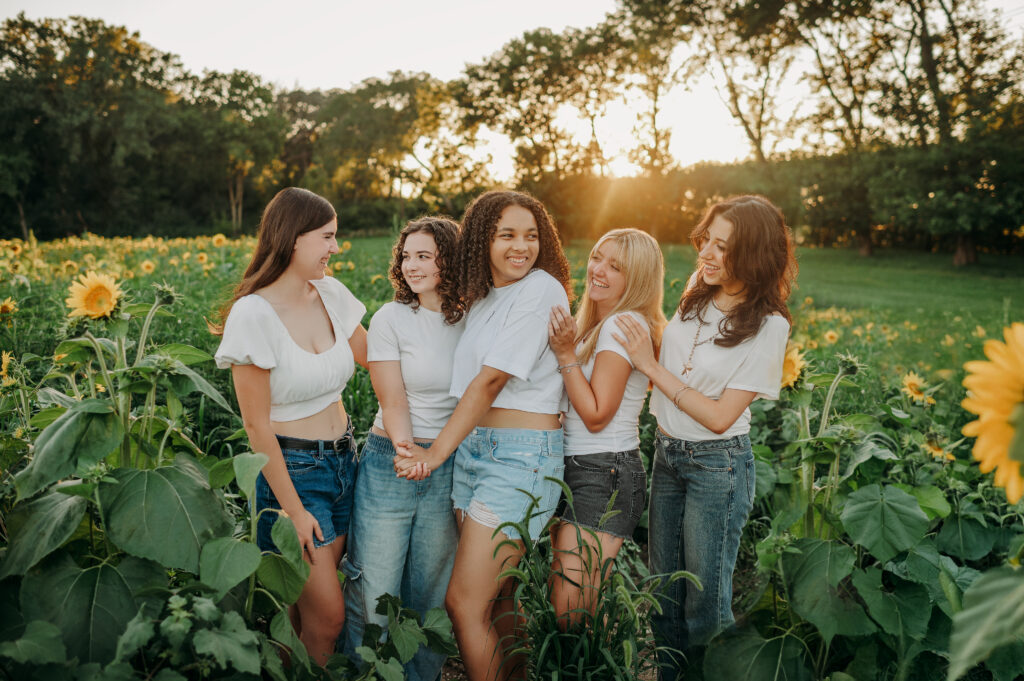 Five senior girls posing together in a sunflower field at golden hour — Barrington IL senior portraits by Kiley Humbert Photography